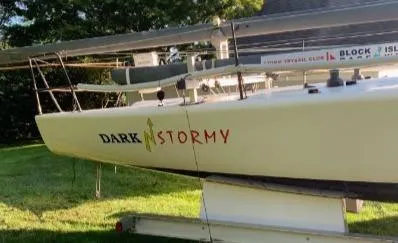 Slide: The Image of Melges 32 sailboat, 2007 model, named "Dark Stormy," on a trailer in a grassy area. - 3