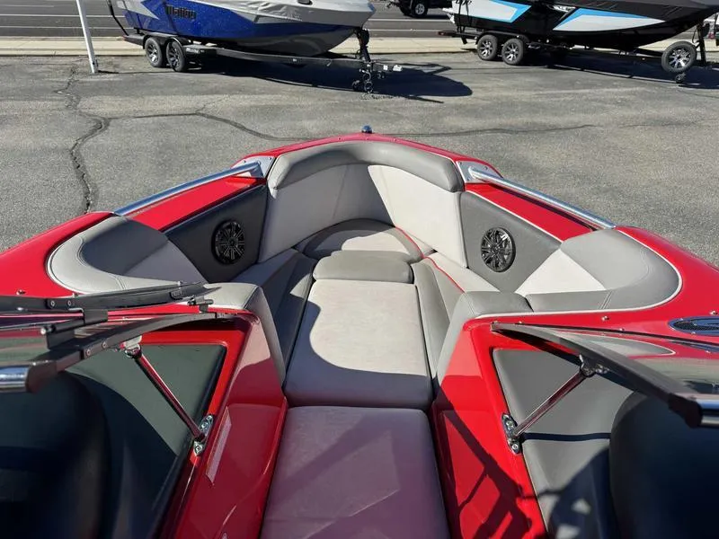 Slide: The Image of 2009 Supra 21V LAUNCH boat interior with red and gray seating, parked on pavement. - 12