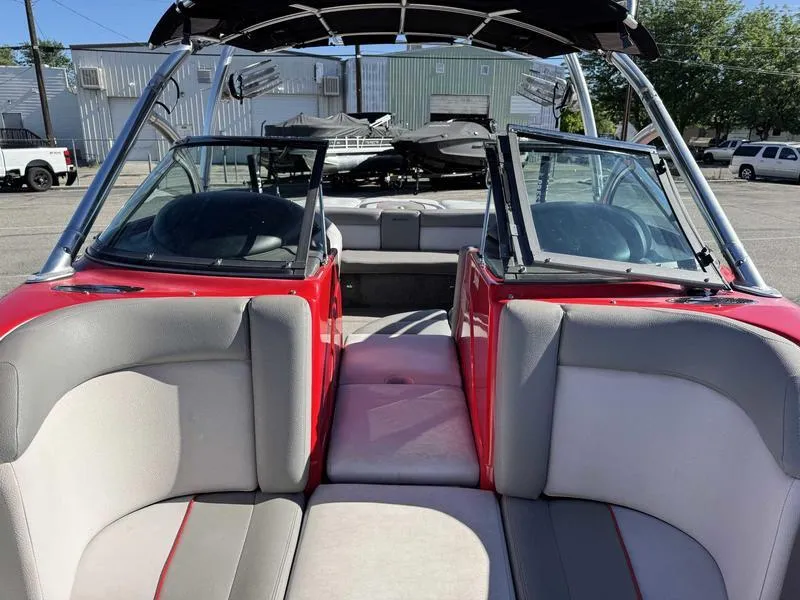 Slide: The Image of 2009 Supra 21V LAUNCH boat interior with red and gray seating, open windshield, and bimini top. - 13