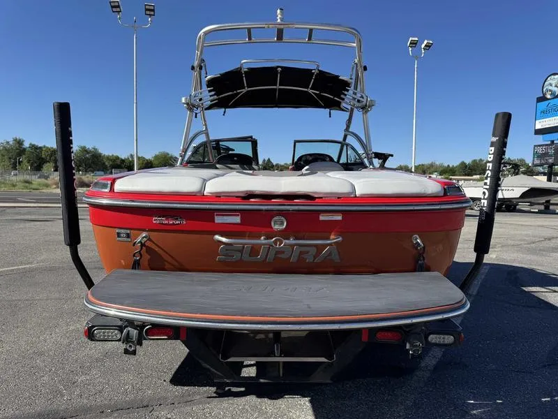 Slide: The Image of 2009 Supra 21V LAUNCH boat, rear view, orange exterior, parked outdoors. - 5
