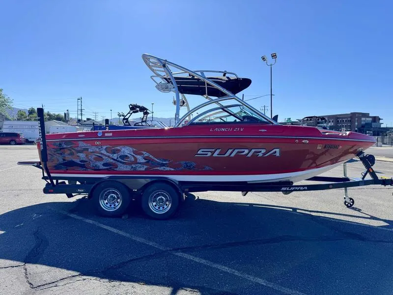 Slide: The Image of 2009 Supra 21V LAUNCH boat on trailer, red with graphics, parked in lot. - 9