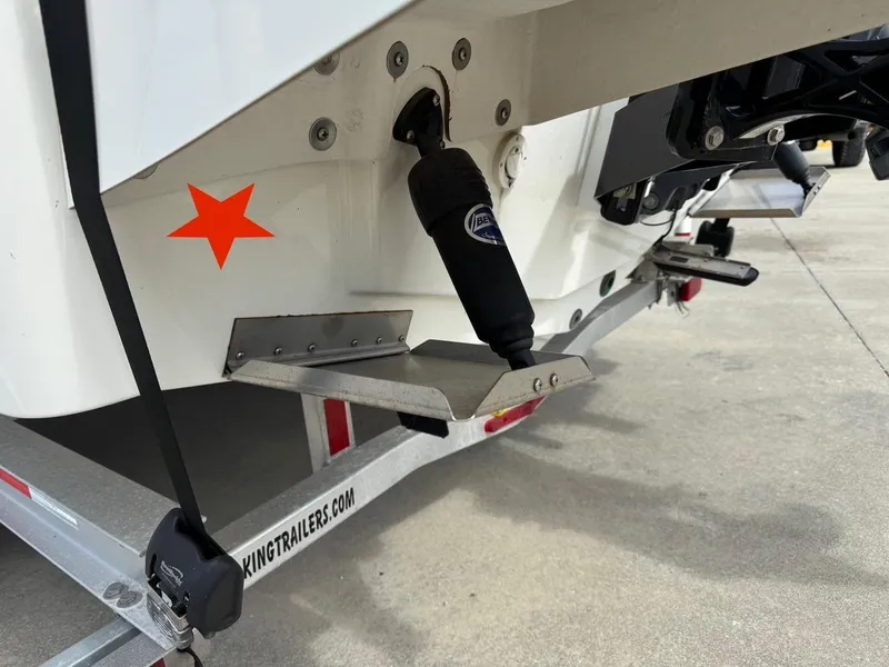 Slide: The Image of 2020 Bay Rider 239 Bay boat on trailer, featuring trim tabs and a red star decal. - 6