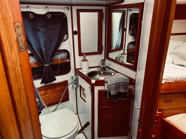Slide: The Image of Compact 1983 Stevens 40 yacht bathroom with sink, toilet, and wooden accents. - 25