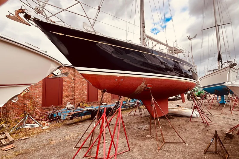 Slide: The Image of 1983 Stevens 40 sailboat on stands in a boatyard, with a brick building backdrop. - 39