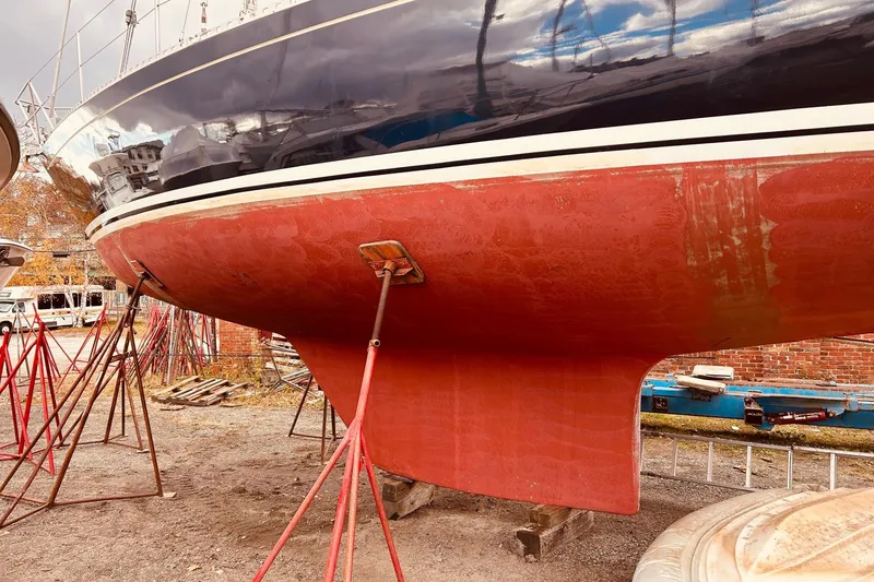 Slide: The Image of 1983 Stevens 40 sailboat on stands, showcasing red hull and keel in a boatyard. - 40