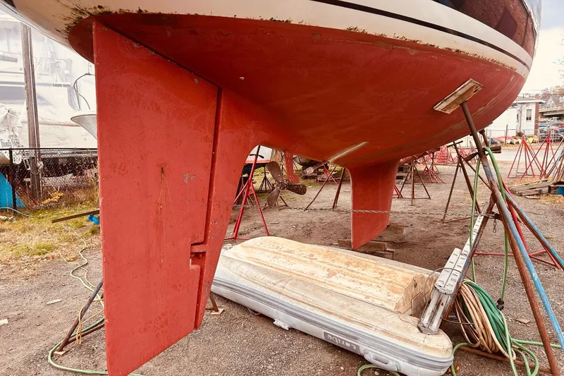 Slide: The Image of Red hull of a 1983 Stevens 40 sailboat on stands, with an inflatable dinghy beneath. - 41