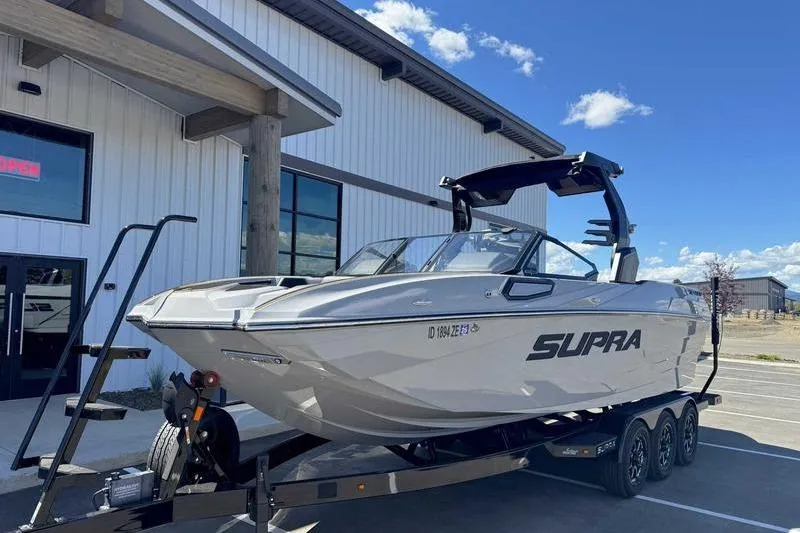 Slide: The Image of 2025 Supra SE boat on trailer outside a modern building under a clear blue sky. - 3