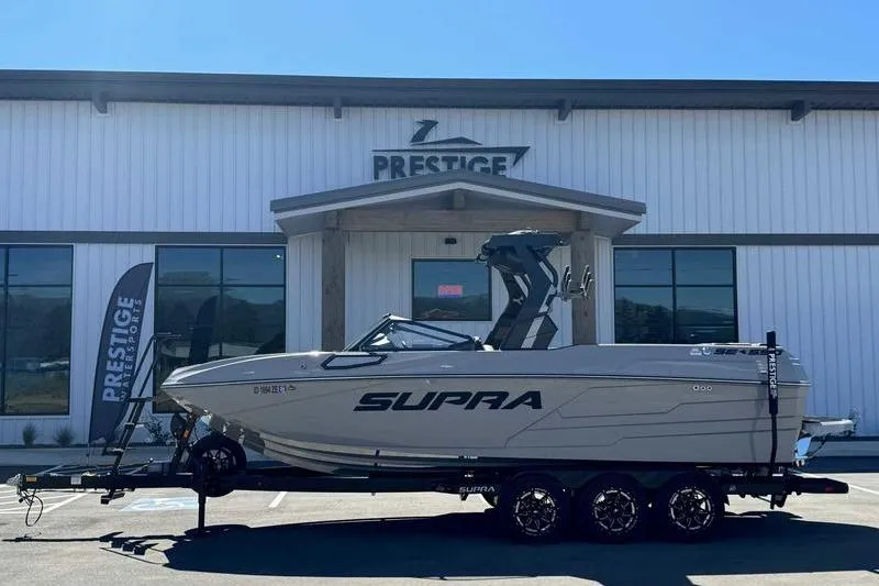 Slide: The Image of 2025 Supra SE boat on trailer outside Prestige building, showcasing sleek design. - 6