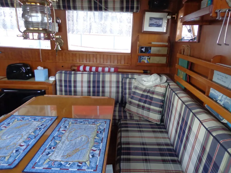 Slide: The Image of 1984 Sundowner Tug Pilothouse interior with wooden cabinetry, dining table, and kitchen area. - 13