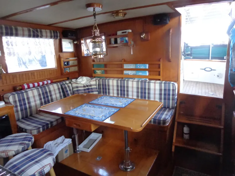 Slide: The Image of 1984 Sundowner Tug Pilothouse kitchen with plaid stools, sink, stove, and seating area. - 16