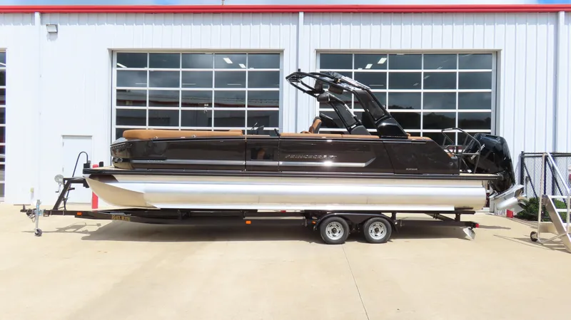The Image of 2025 Princecraft Vogue 27 RL pontoon boat on trailer, parked outside a building. - 1