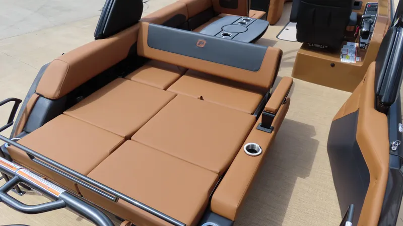 Slide: The Image of 2025 Princecraft Vogue 27 RL boat interior with tan and black seating, cup holders, and control panel. - 9