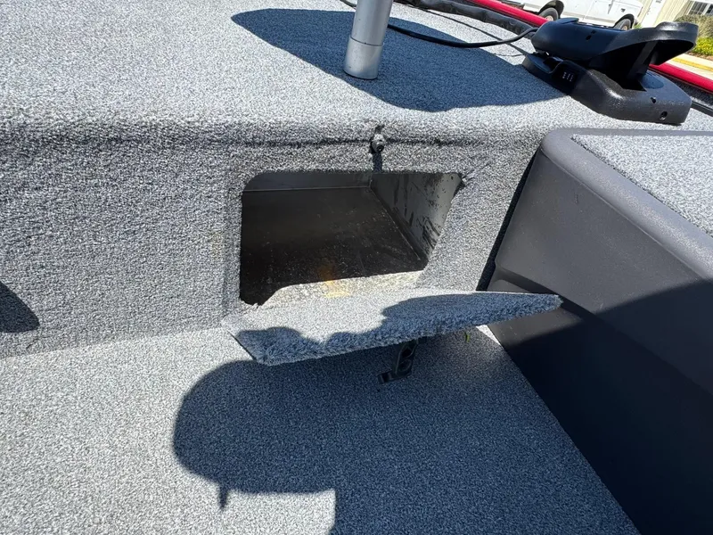 Slide: The Image of 2020 Bass Tracker Classic 16 boat storage compartment with open hatch, gray carpeted interior. - 11