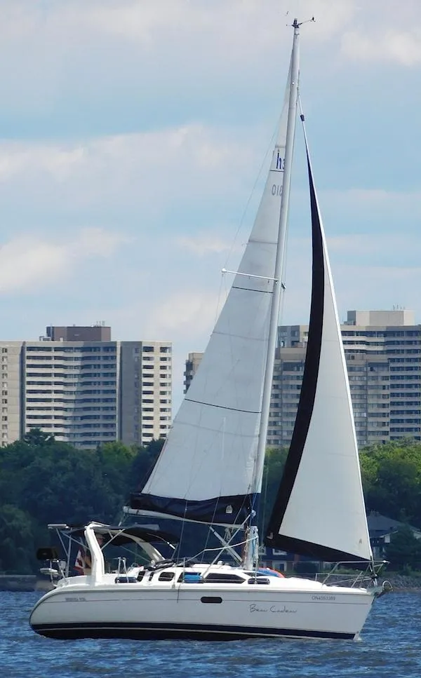 The Image of Sailboat Hunter 310, 1997 model, cruising on water with cityscape background. - 1
