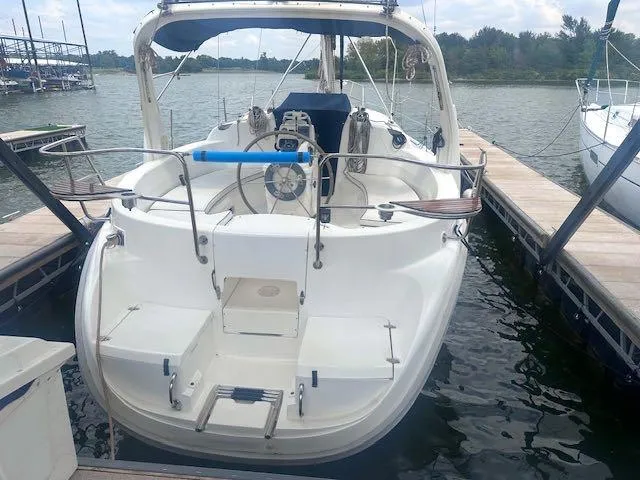 Slide: The Image of 1997 Hunter 310 sailboat docked, featuring spacious cockpit and dual steering wheels. - 3