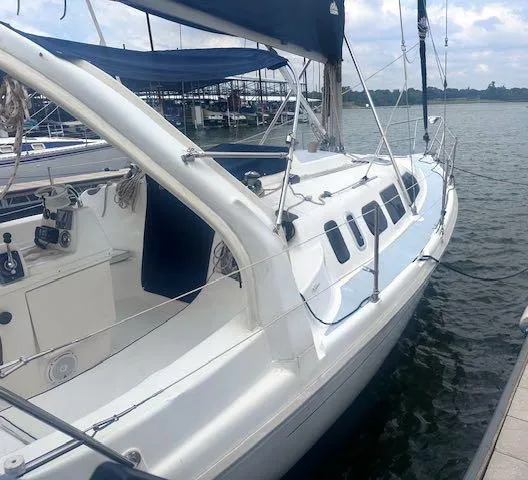 Slide: The Image of 1997 Hunter 310 sailboat docked by the water, featuring sleek white design and blue accents. - 4