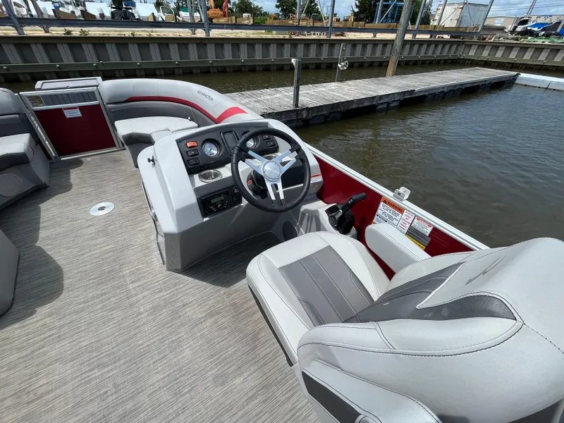 Slide: The Image of 2022 Bennington 22SSRCX pontoon boat interior with steering wheel and seating at dock. - 11
