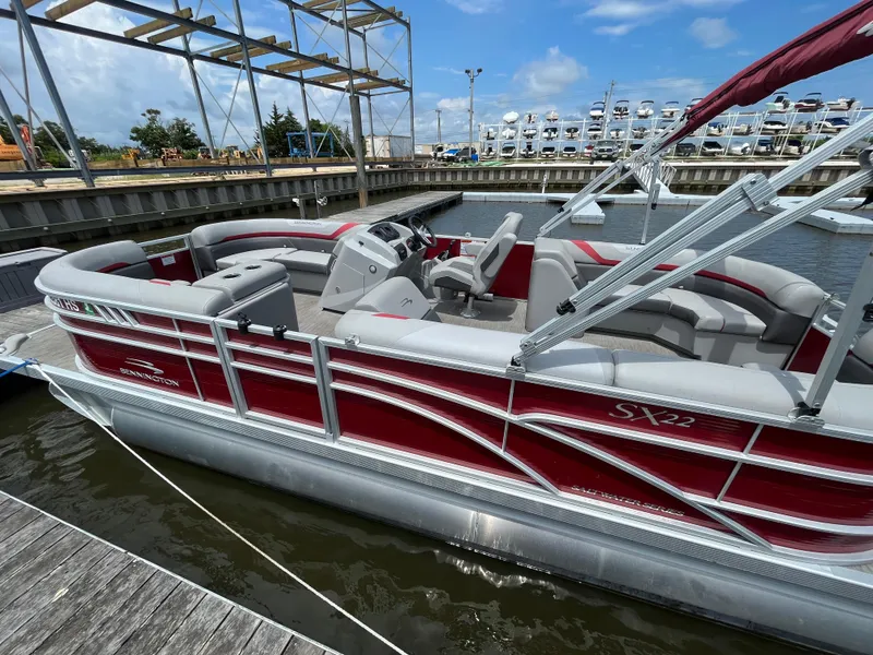 Slide: The Image of 2022 Bennington 22SSRCX pontoon boat docked, featuring red and silver design, spacious seating. - 2