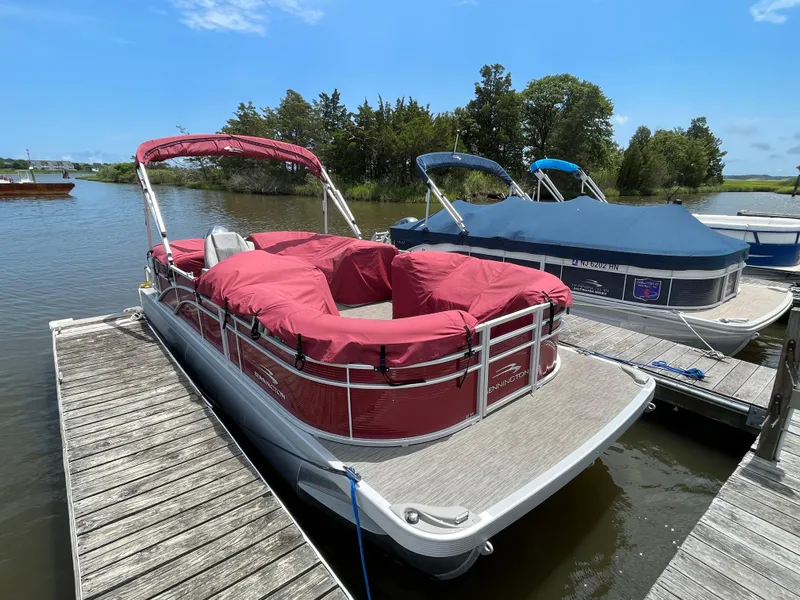 Slide: The Image of 2022 Bennington 22SSRCX pontoon boat docked with red cover, sunny day. - 3