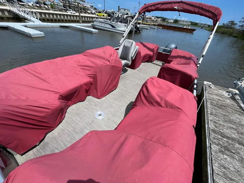 Slide: The Image of 2022 Bennington 22SSRCX pontoon boat with red covers docked at marina. - 4