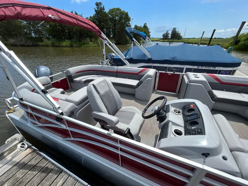 Slide: The Image of 2022 Bennington 22SSRCX pontoon boat with red canopy, docked on a calm river. - 6
