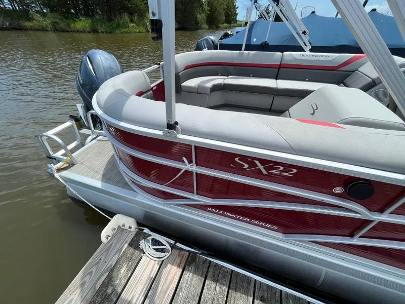 Slide: The Image of 2022 Bennington 22SSRCX pontoon boat docked on a calm lake. - 8