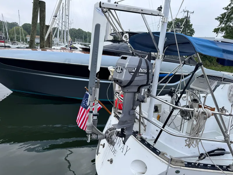 Slide: The Image of 1981 C&C 37 sailboat with Johnson outboard motor and American flag at marina. - 14