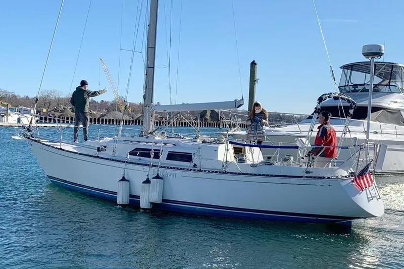 Slide: The Image of 1981 C&C 37 sailboat with three people onboard, docked in a marina. - 2