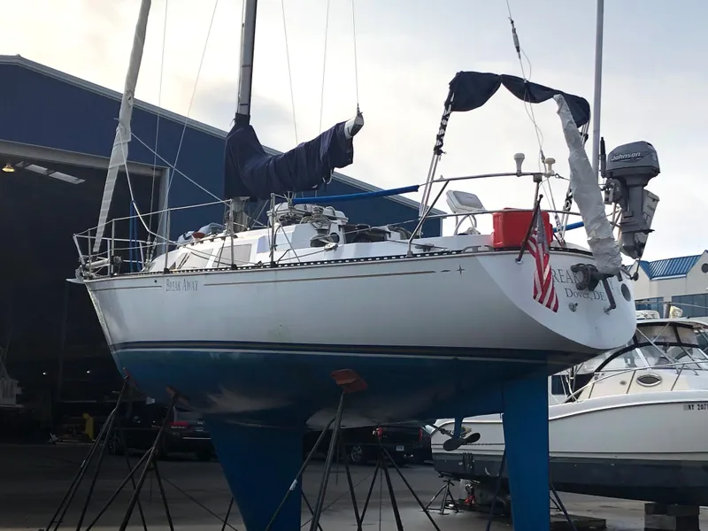 Slide: The Image of 1981 C&C 37 sailboat on stands in a marina, with blue hull and covered sails. - 20