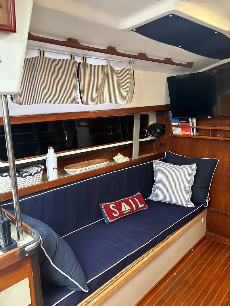 Slide: The Image of Interior of 1981 C&C 37 sailboat with cozy seating, striped curtains, and nautical decor. - 24