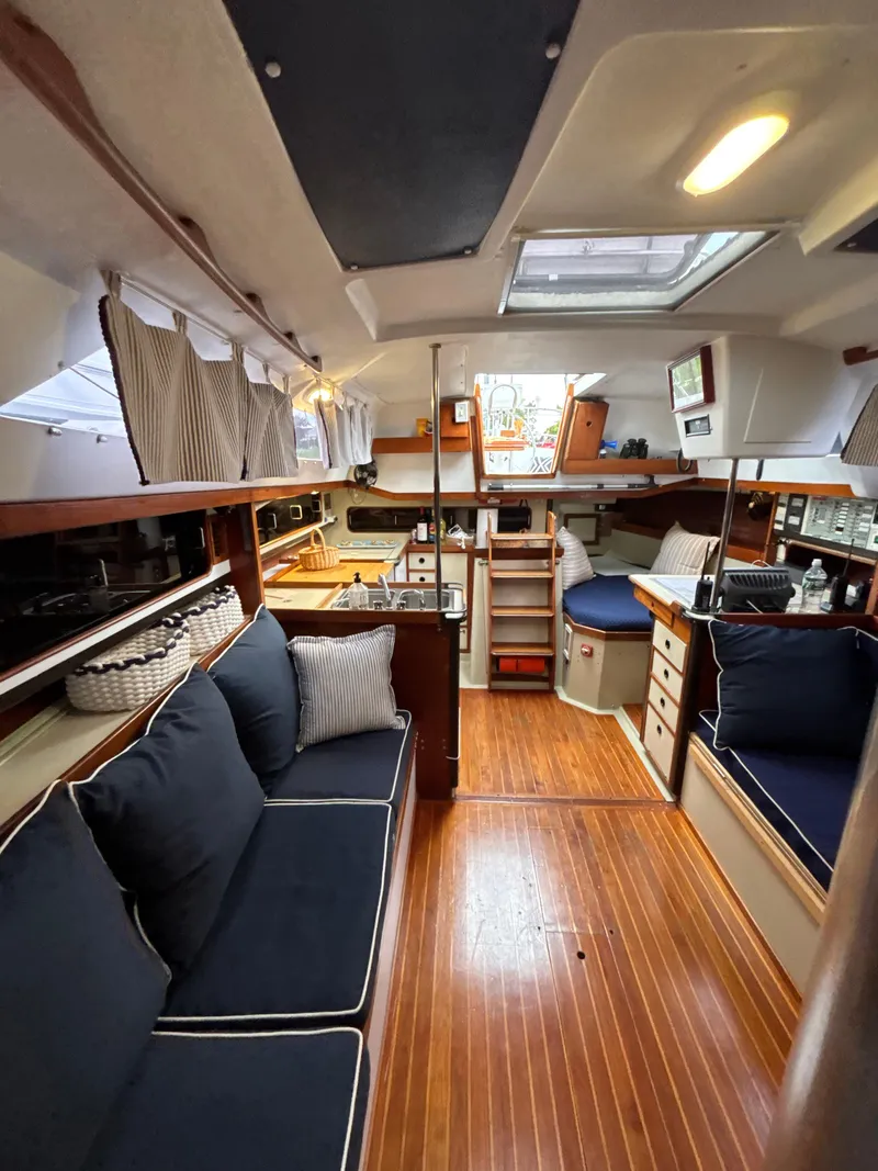 Slide: The Image of Interior of a 1981 C&C 37 sailboat with wooden flooring and navy cushions. - 28