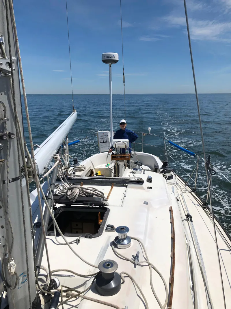 Slide: The Image of 1981 C&C 37 sailboat on open water, clear sky, person at helm. - 7
