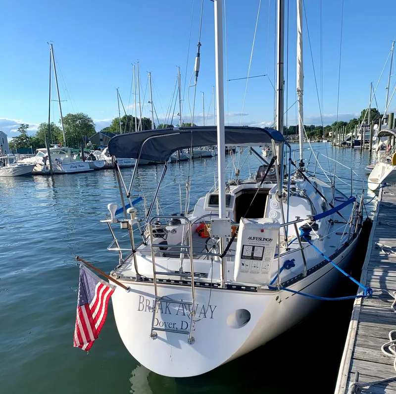 Slide: The Image of 1981 C&C 37 sailboat docked, displaying American flag, sunny marina setting. - 8