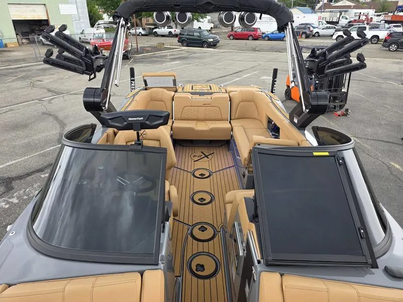Slide: The Image of 2025 MasterCraft X24 boat interior with tan seating and advanced audio system. - 15