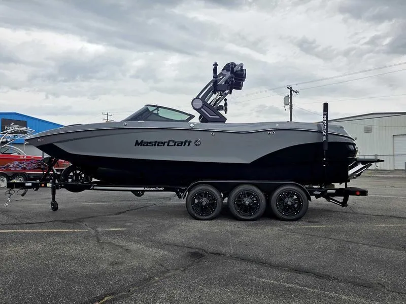Slide: The Image of 2025 MasterCraft X24 boat on trailer, parked outdoors under cloudy sky. - 6