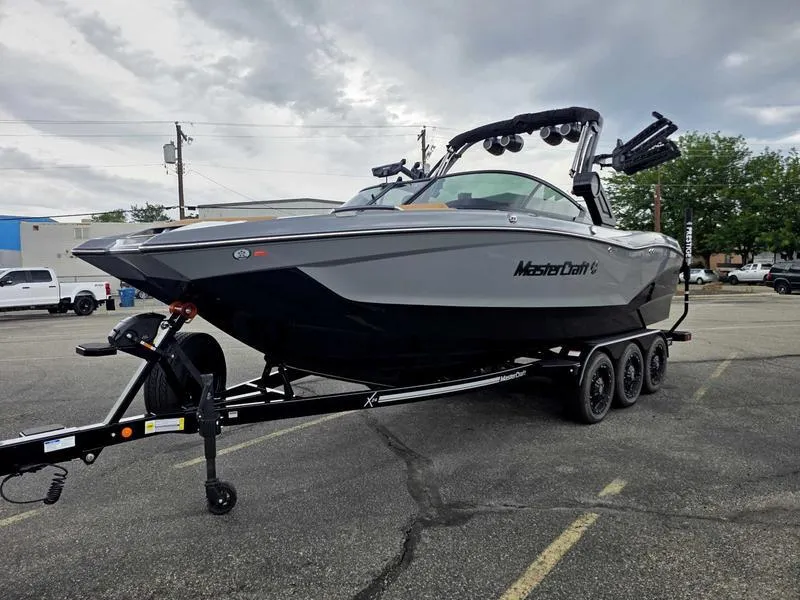 Slide: The Image of 2025 MasterCraft X24 boat on trailer in parking lot under cloudy sky. - 7