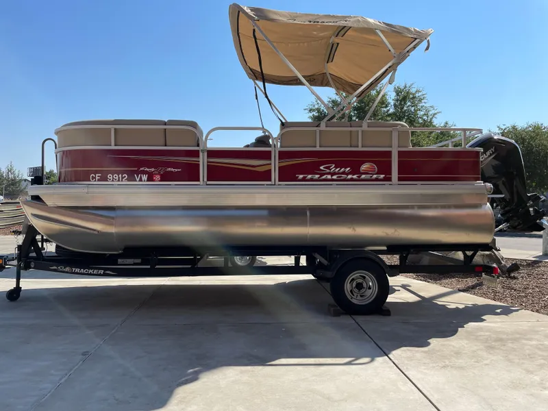 The Image of 2024 Sun Tracker Party Barge 18 DLX pontoon boat on trailer, parked outdoors. - 0
