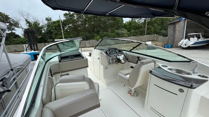 Slide: The Image of 2013 Sea Ray 270 SLX boat interior with helm, seating, and sink, docked outdoors. - 14