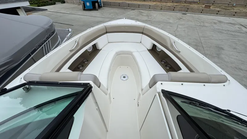 Slide: The Image of 2013 Sea Ray 270 SLX boat interior with white and beige seating, docked outdoors. - 25