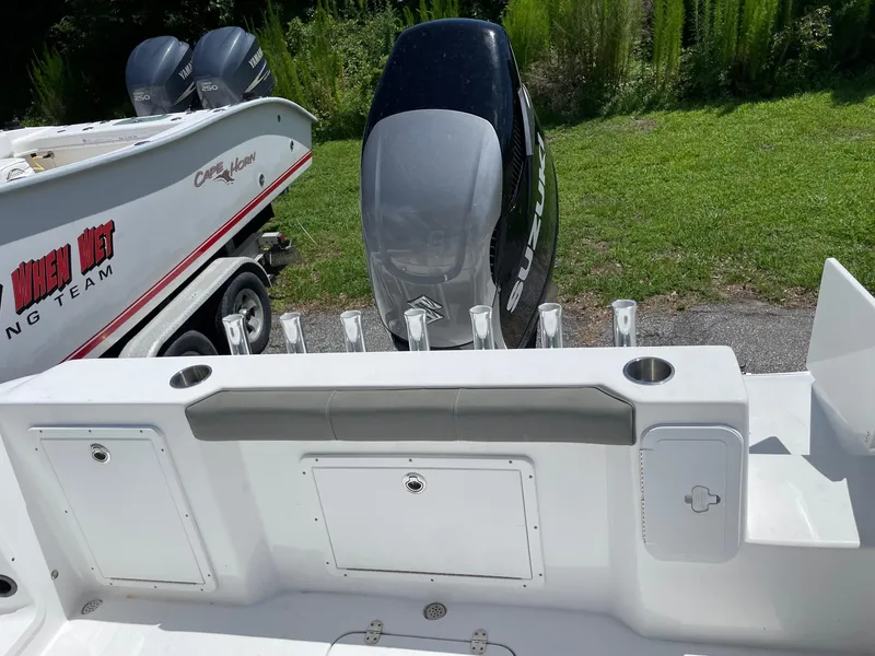 Slide: The Image of 2021 Cape Horn 22 OS boat with Suzuki outboard motor and rod holders, parked on grass. - 19