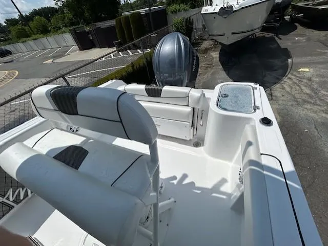 Slide: The Image of 2025 Wellcraft 222 Fisherman boat interior with seating and outboard motor in a parking area. - 5