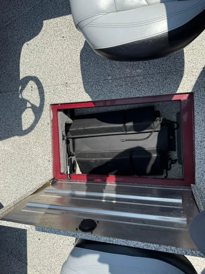 Slide: The Image of 2012 Tracker Targa V-18 Combo boat storage compartment with open lid and visible seating. - 17