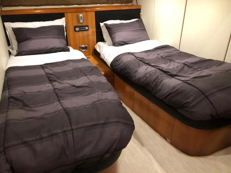Slide: The Image of Twin beds in a 2003 Sunseeker Portofino 46 yacht cabin, featuring dark bedding. - 14