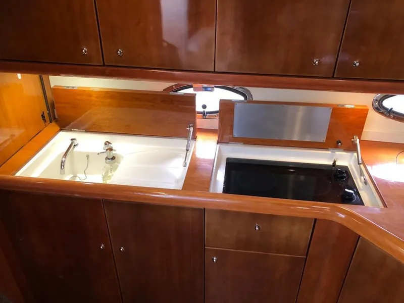 Slide: The Image of 2003 Sunseeker Portofino 46 yacht kitchen with wooden cabinets, sink, and stove. - 16