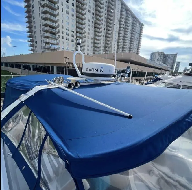 Slide: The Image of 2003 Sunseeker Portofino 46 yacht with blue canopy and Garmin radar, docked near high-rise buildings. - 33