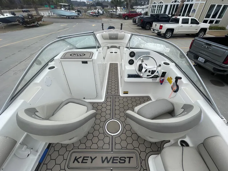 Slide: The Image of 2021 Key West 203 DFS boat interior with steering wheel and seating, parked in a marina. - 5
