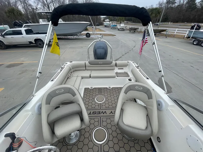 Slide: The Image of 2021 Key West 203 DFS boat interior with seating, flags, and deck view at a marina. - 6