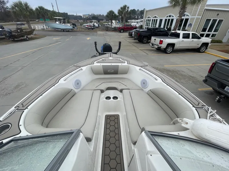 Slide: The Image of 2021 Key West 203 DFS boat interior with seating, parked near vehicles and palm trees. - 7