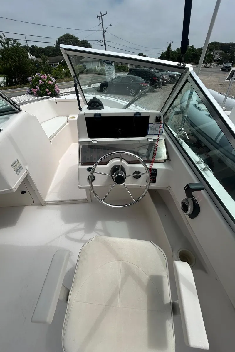 Slide: The Image of 1999 Grady-White 192 Tournament boat interior with steering wheel and seating, parked outdoors. - 9