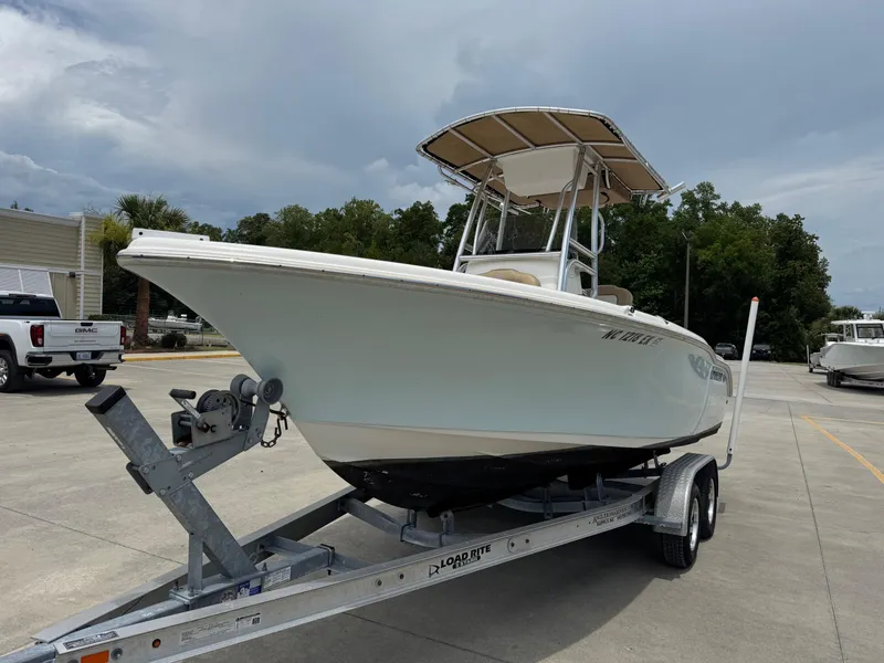 Slide: The Image of 2019 Key West 219 FS boat on trailer, parked outdoors under cloudy sky. - 2